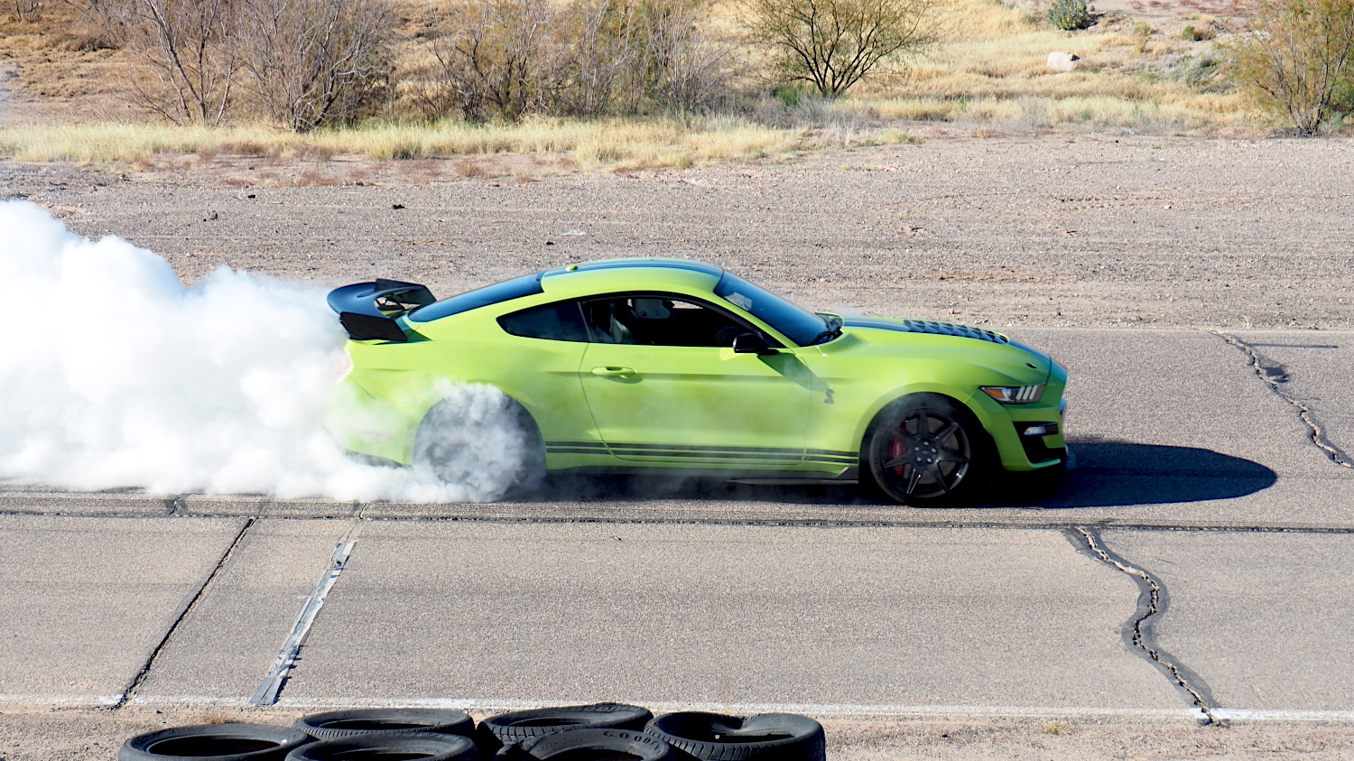 Green Mustang on track smoking the tires