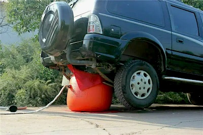 Exhaust jack lifting an SUV's rear.