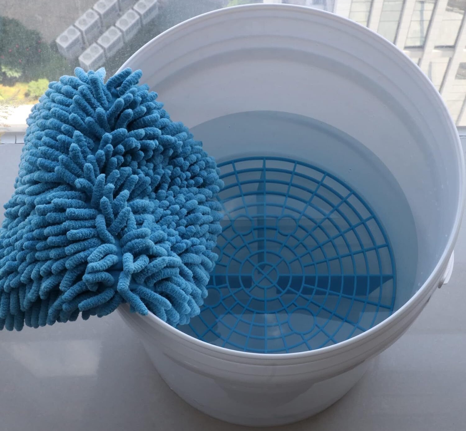 A microfiber wash mitt and wash bucket equipped with a grit guard.